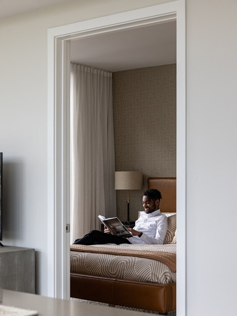 a man sitting on a bed using a laptop computer