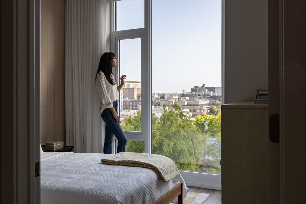 a woman looking out of a window in a hotel room