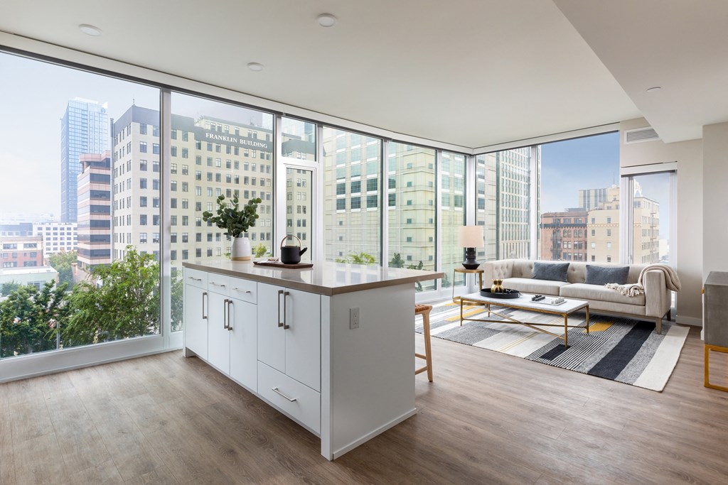 a living room with a large window and a kitchen