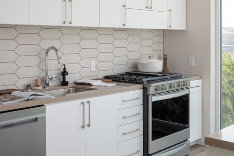a small kitchen with white cabinets and a stove and sink