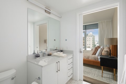a ensuite bathroom with a large mirror and a bedroom with a bed