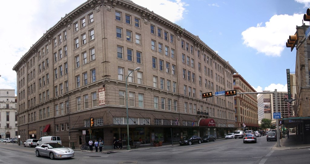 A large building with a lot of windows is in the middle of a street.