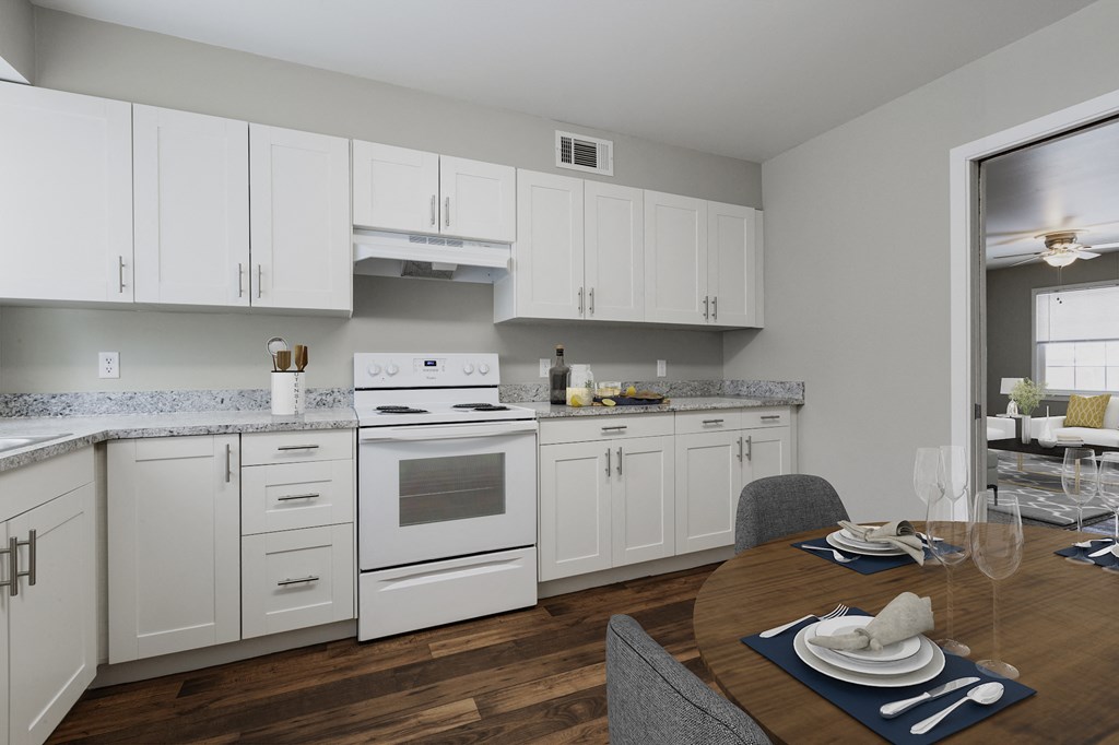 a kitchen with white appliances and white cabinets and a dining table