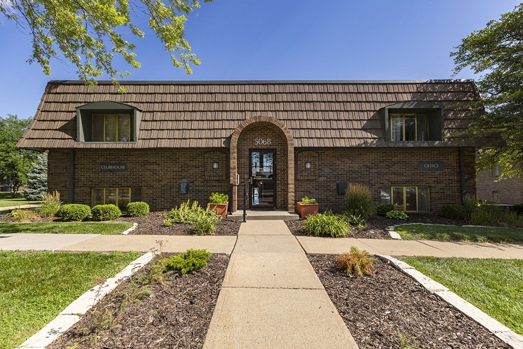 the front of a brick building with a sidewalk and grass