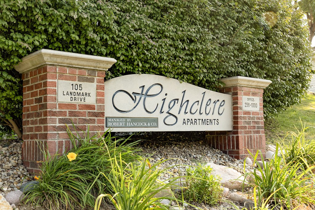 A sign for Highclere Apartments is displayed in front of a green hedge.