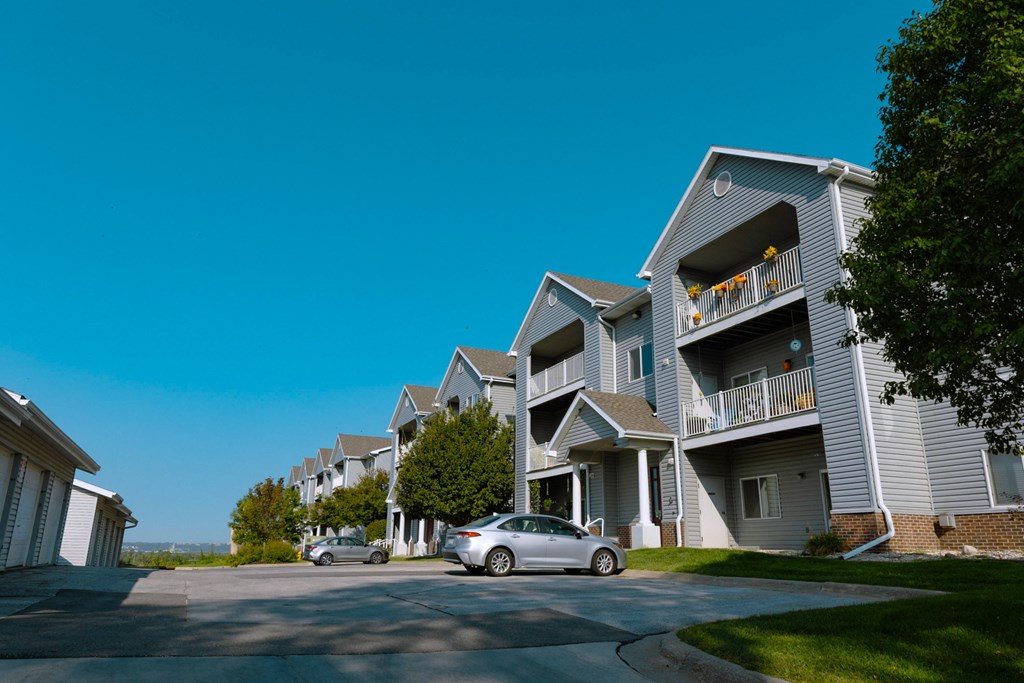 A car is parked on a street in front of apartment buildings.