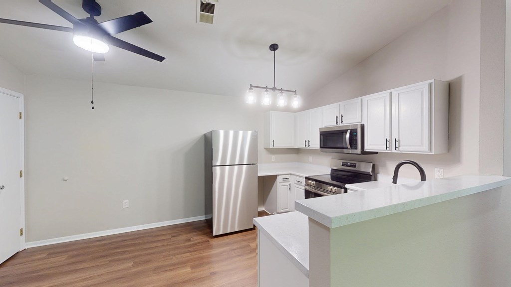 A kitchen with a refrigerator, microwave, and oven.