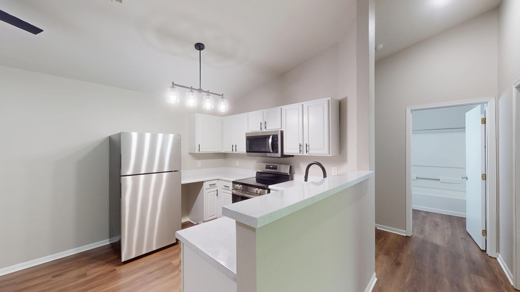 A kitchen with a refrigerator, microwave, and oven.