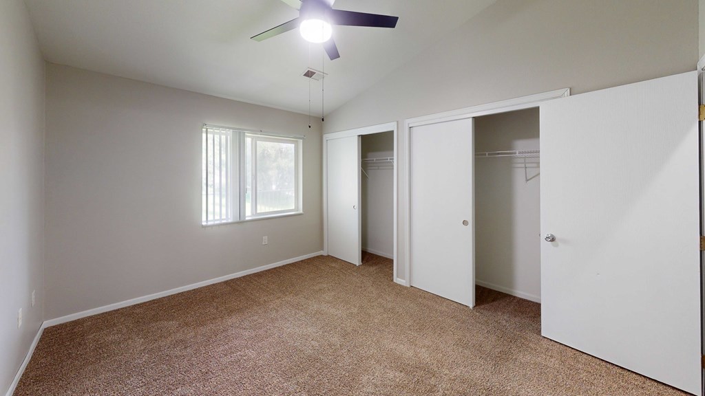 A room with a ceiling fan and carpeted floor.