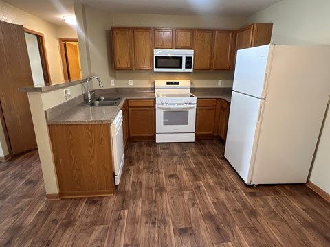 A kitchen with a white refrigerator, wooden cabinets, and a white stove top oven.