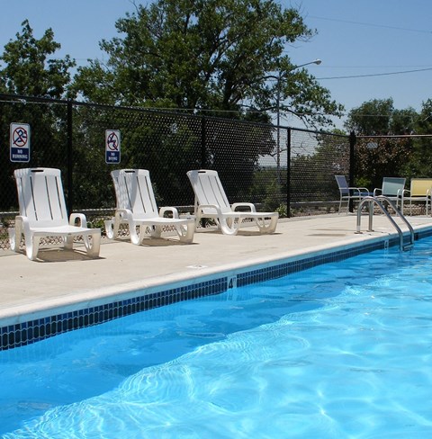 A pool with chairs and signs on a fence.