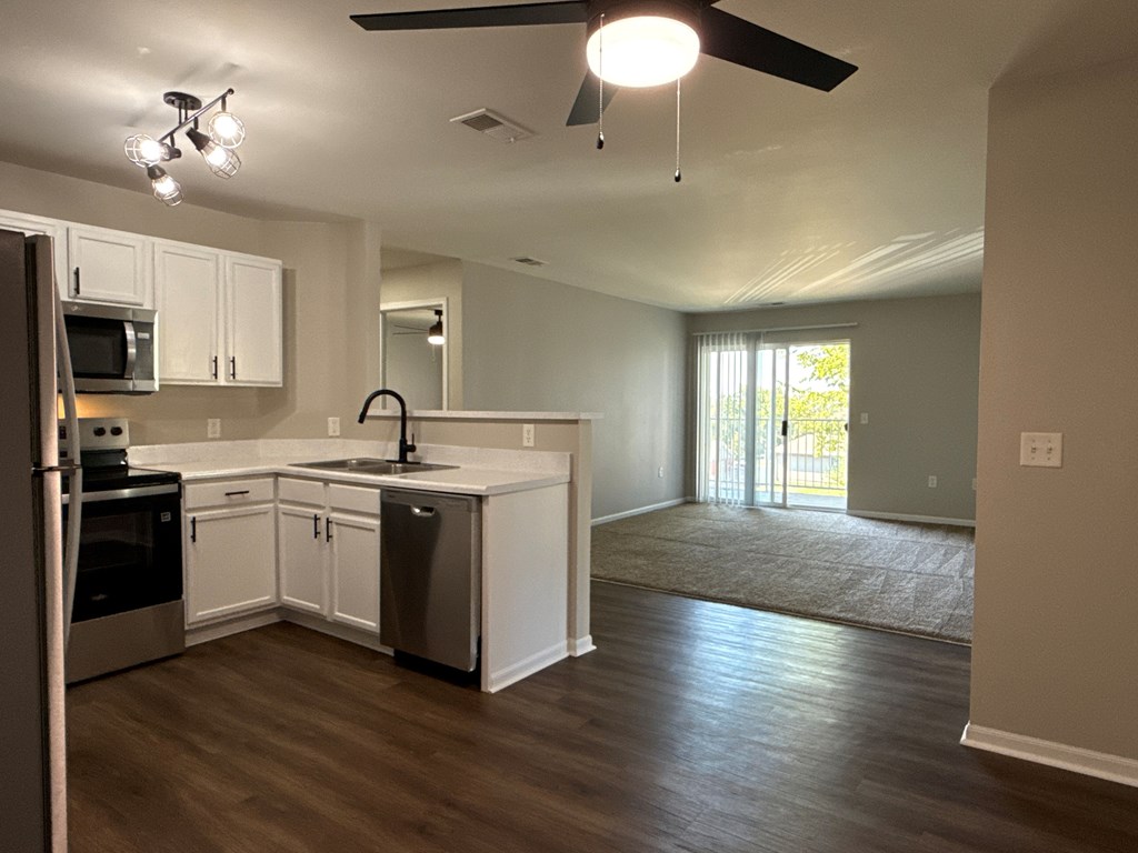 A kitchen with white cabinets and a wooden floor.