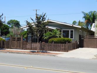 a house with a wooden fence in front of a street
