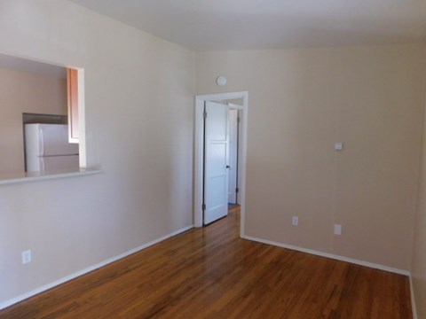 an empty living room with a hard wood floor and white walls