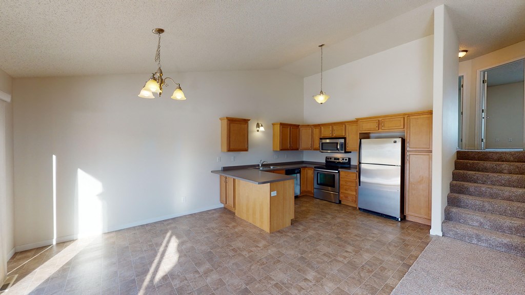 an empty kitchen with wooden cabinets and a stainless steel refrigerator