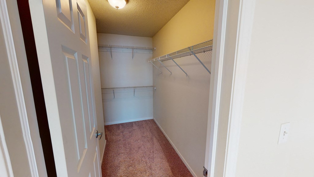a walk in closet with a white door and a white wall with a hanging rack