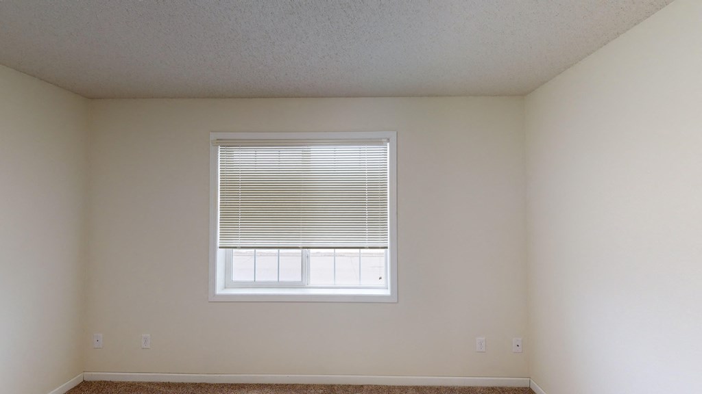 an empty room with a window and white walls