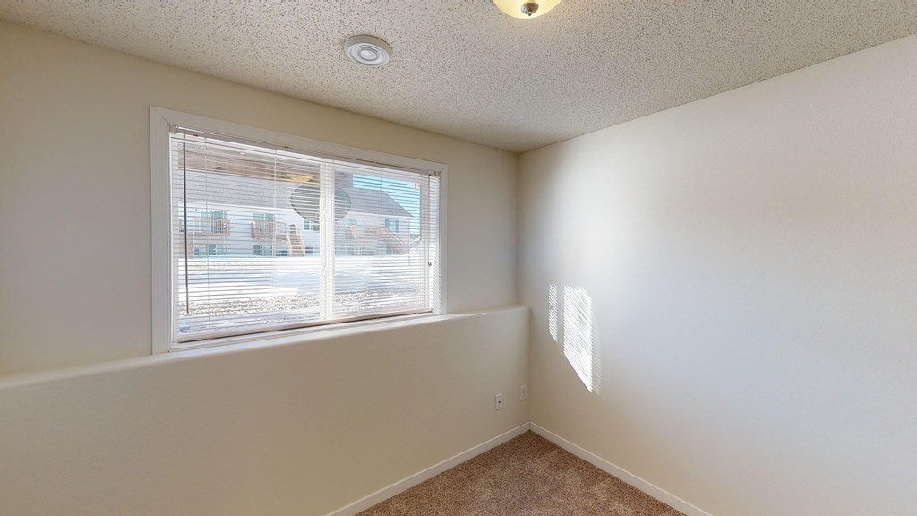 an empty bedroom with a large window and white walls