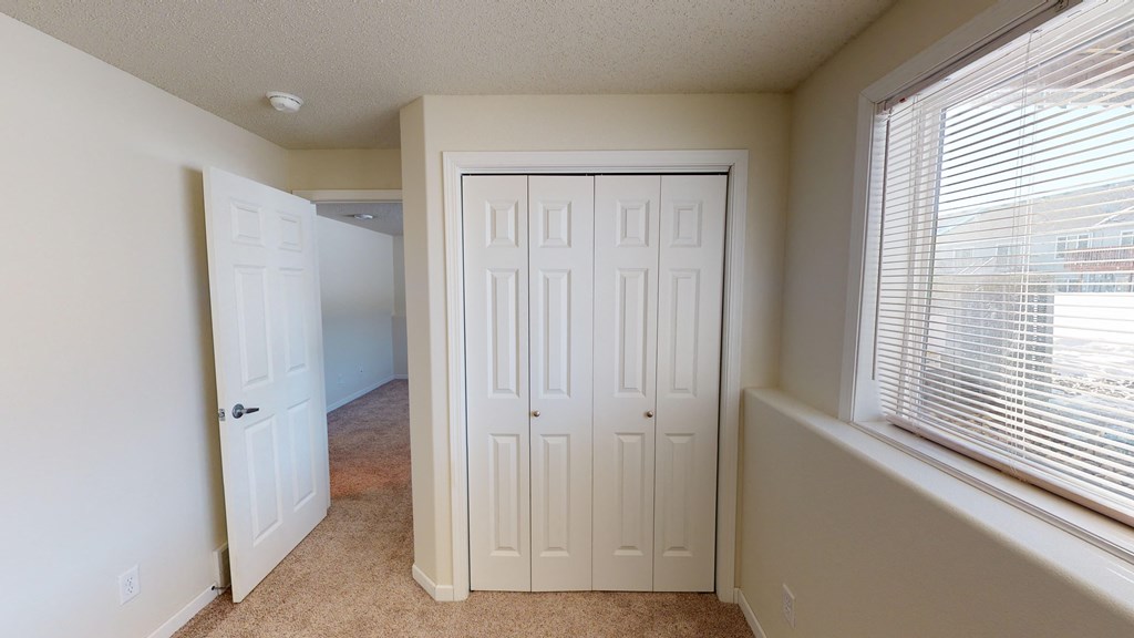 an empty room with a closet and a window and a door