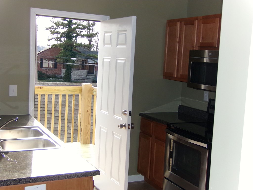 a kitchen with a door open to a deck with a view of a cabin