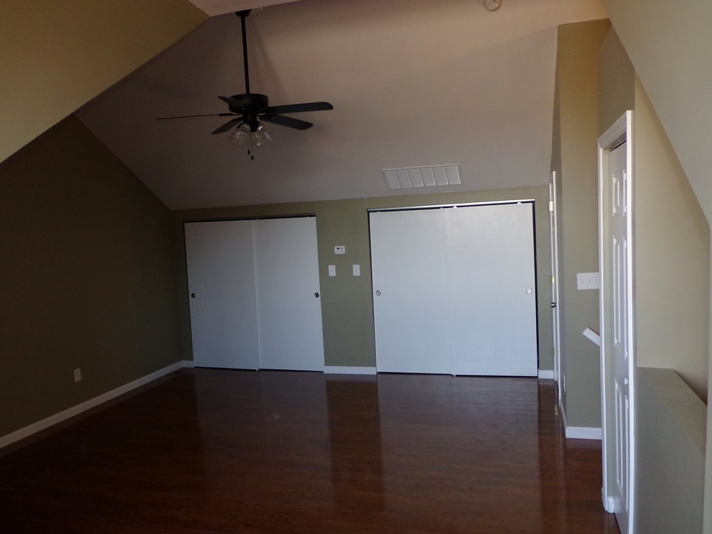 an empty living room with a ceiling fan and