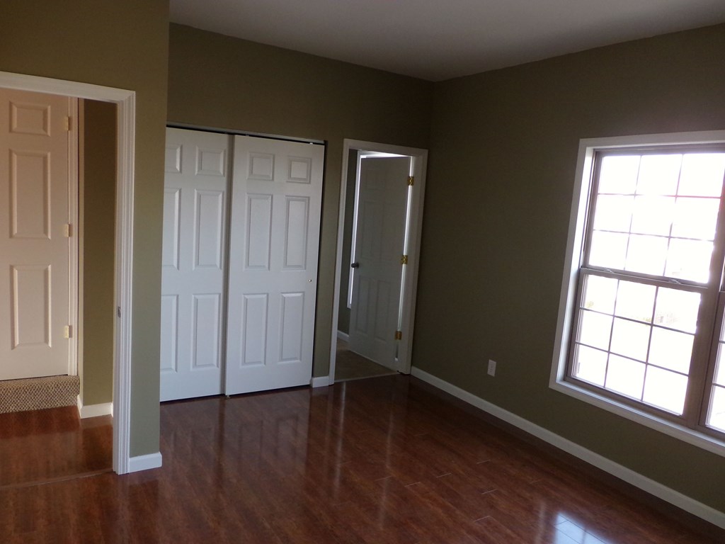 an empty living room with a hard wood floor and two doors