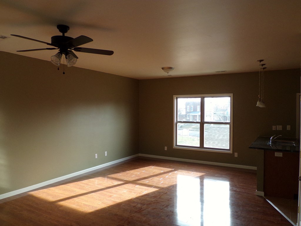 an empty living room with a ceiling fan and a window