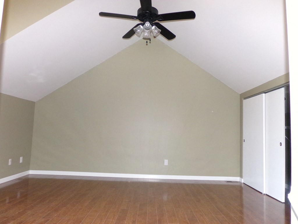 an empty living room with a ceiling fan
