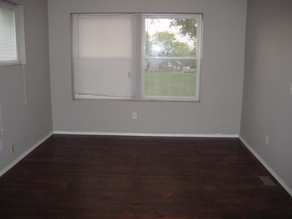 an empty room with wood floors and a window