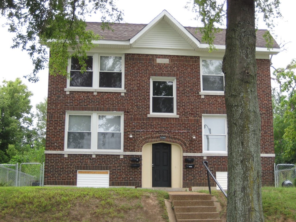 a red brick house with a tree in front of it