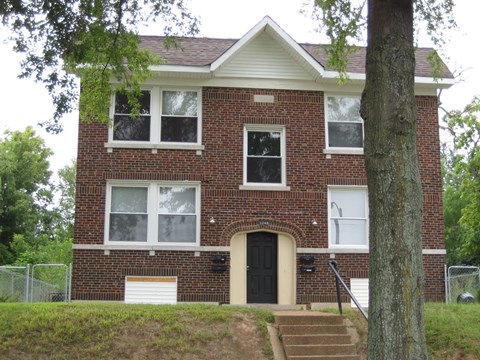 a red brick house with a tree in front of it