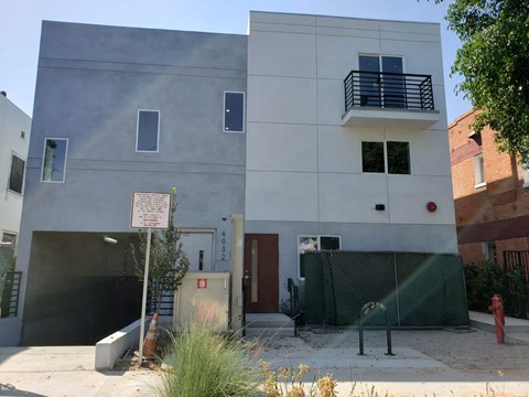 a white building with a fence and a sign in front of it