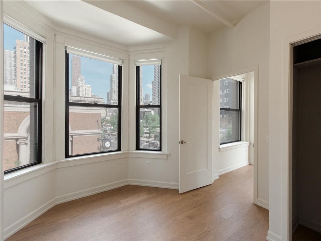 an empty living room with three windows and a door