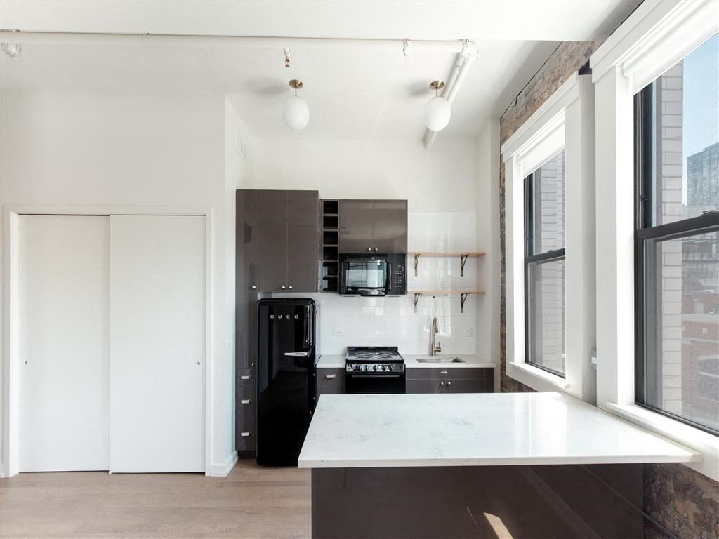 a white kitchen with black appliances and a large window