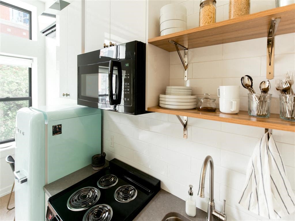 a small kitchen with a black stove and a microwave