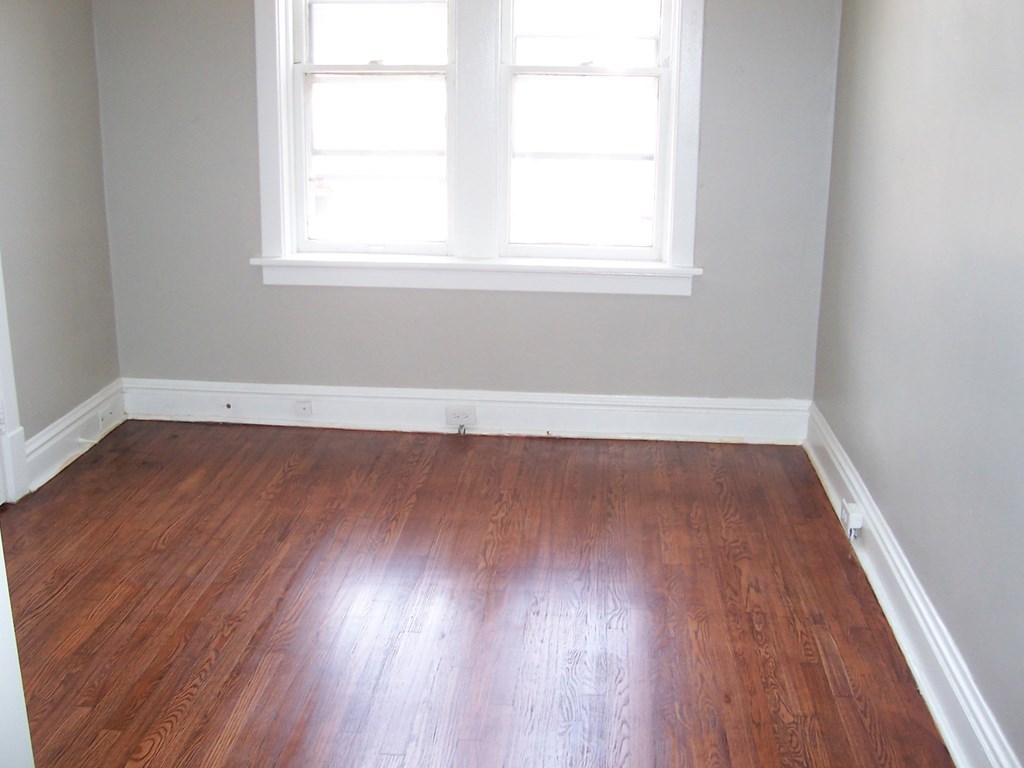 an empty room with wooden floors and a window