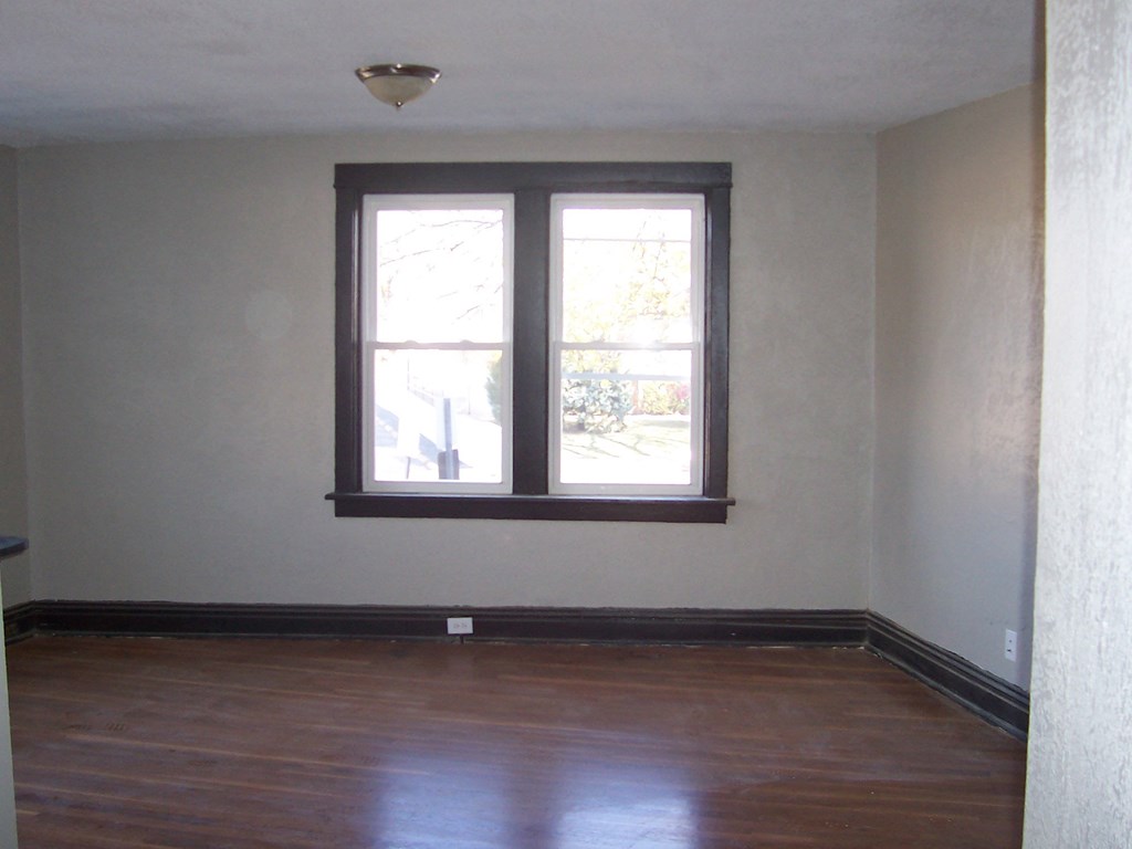 an empty room with a window and wooden floors