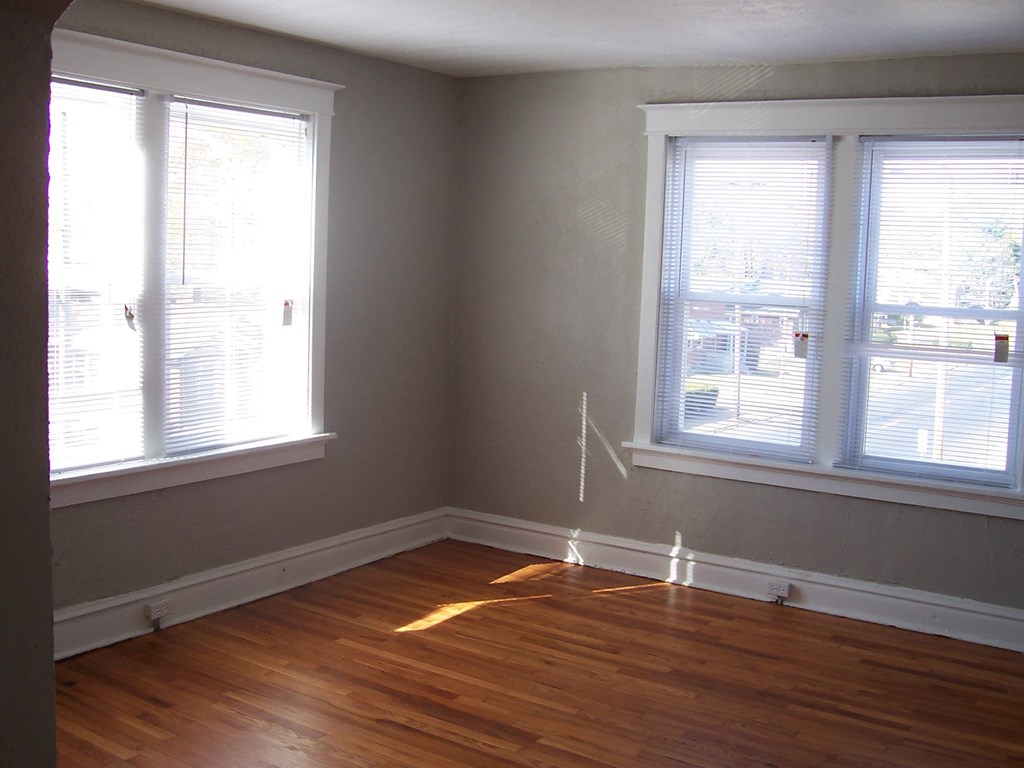 a room with wood floors and three windows