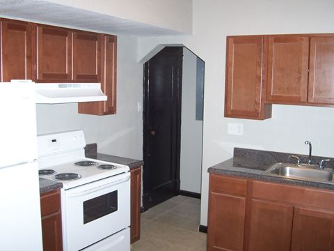 a kitchen with a stove and sink and a black door