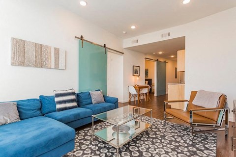 a living room with a blue couch and a glass table