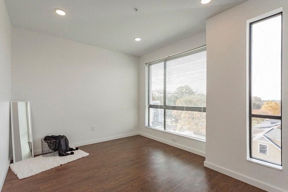 an empty living room with a large window and wood floors
