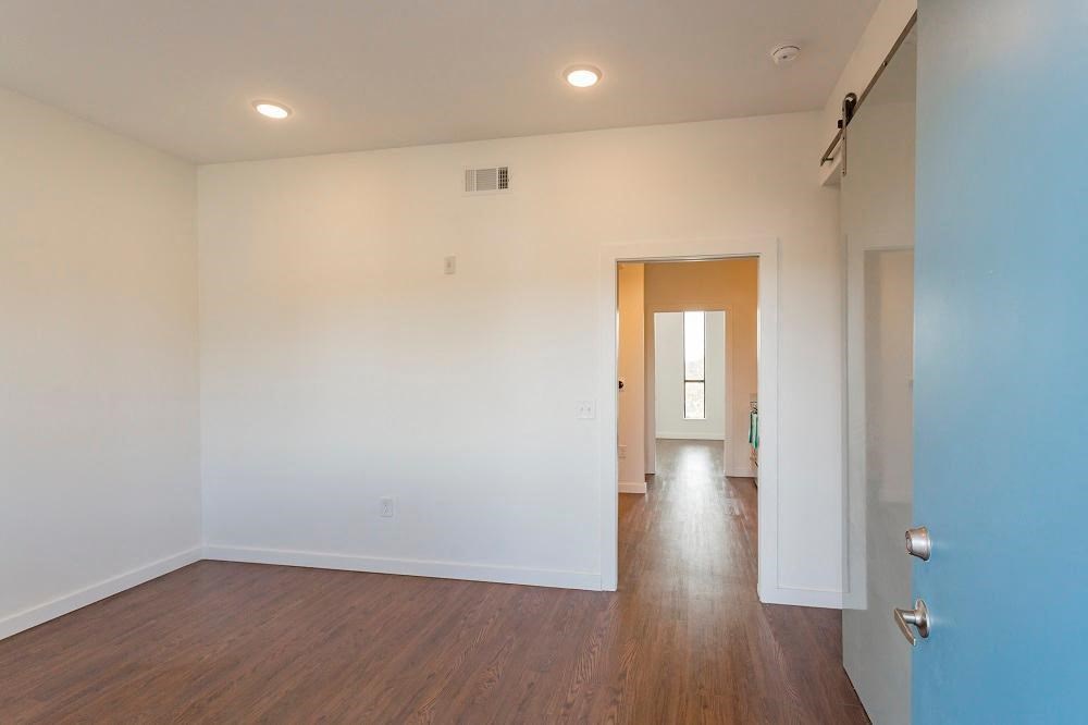 an empty living room with a blue wall and wood floors