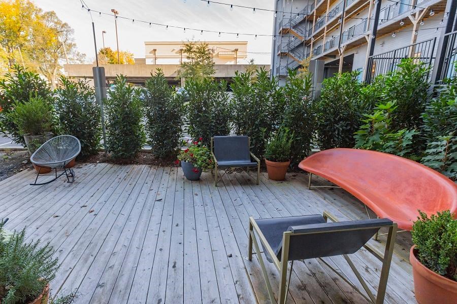 a patio with a bench and chairs and plants