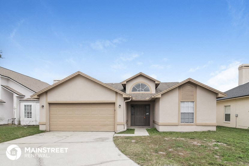 a beige house with a driveway and a garage door