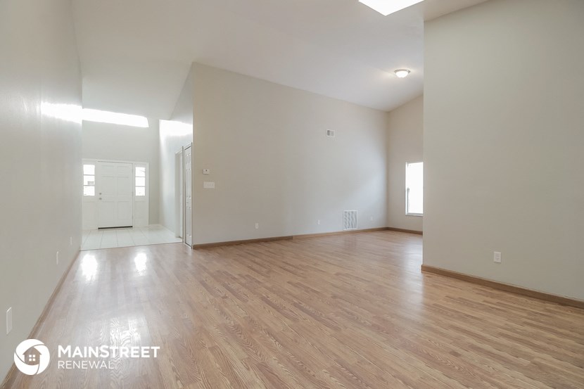 the living room and dining room with wood flooring and white walls