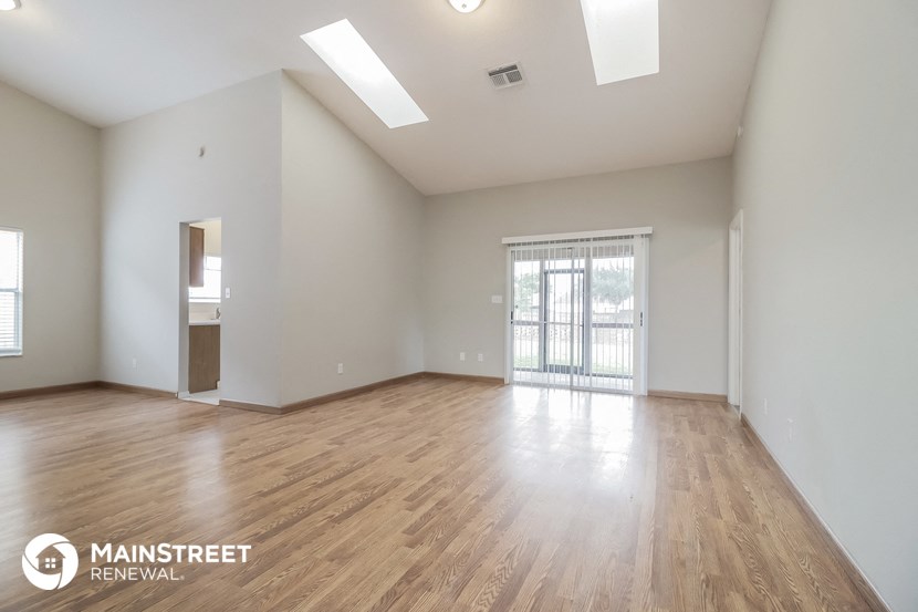 the spacious living room with wood flooring and a large window