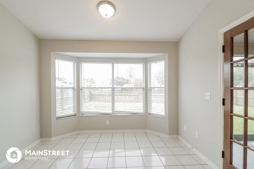 an empty living room with large windows and a tiled floor