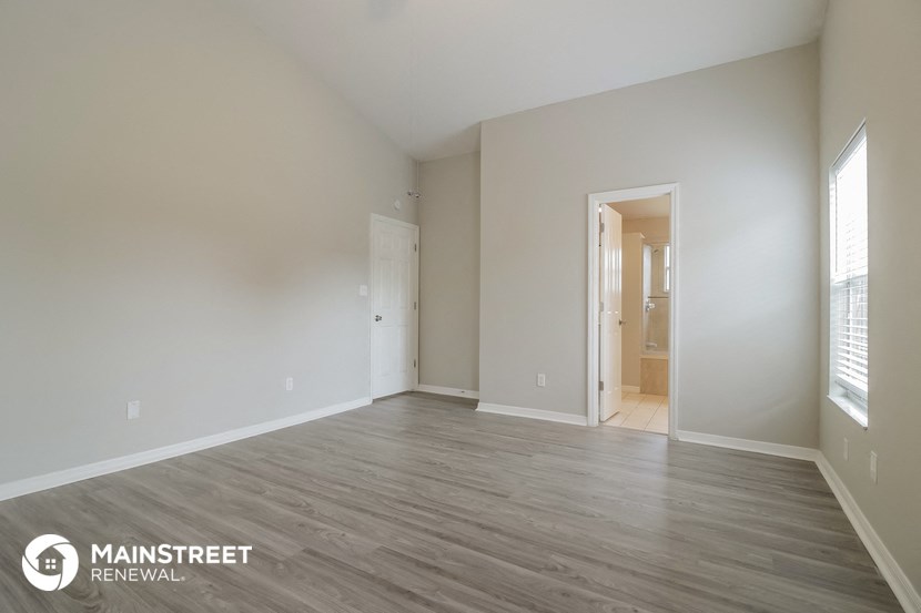 a spacious living room with white walls and wood flooring