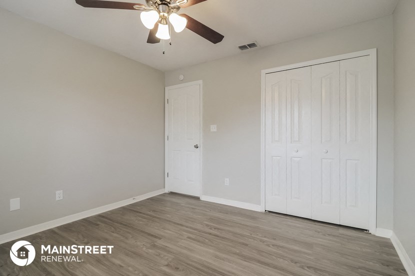 the spacious living room with ceiling fan and white doors