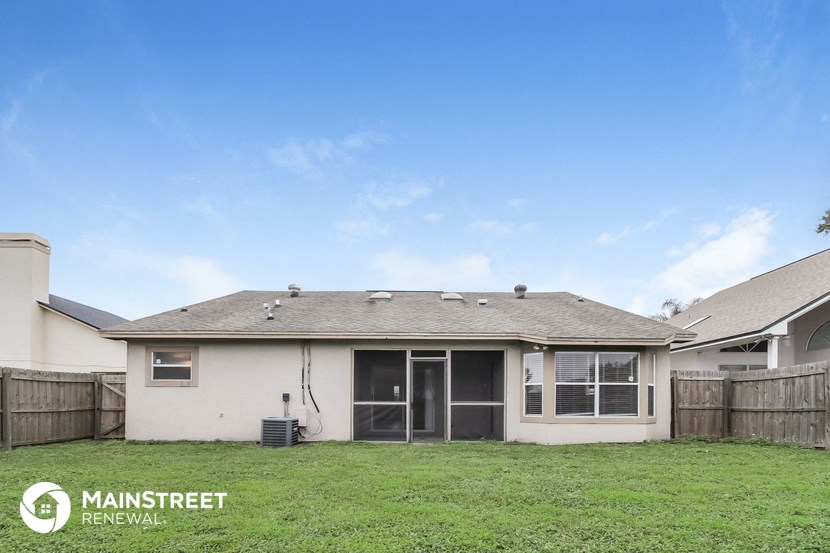 a view of the backyard of a home with a lawn and a fence